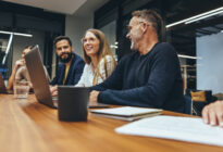 Kollegen verschiedener Ethnien sitzen im Meeting vor ihrem Laptop