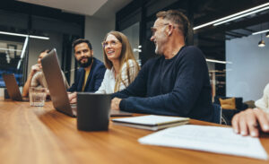 Kollegen verschiedener Ethnien sitzen im Meeting vor ihrem Laptop