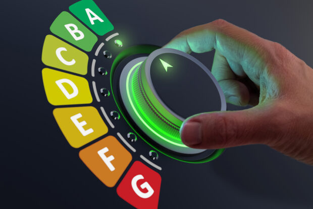 Hand dreht an grünem Button bei Skala mit mehreren Buchstaben