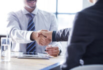 Zwei männliche Businessleute schütteln sich im Büro gegenseitig die Hand
