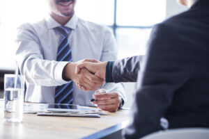 Zwei männliche Businessleute schütteln sich im Büro gegenseitig die Hand