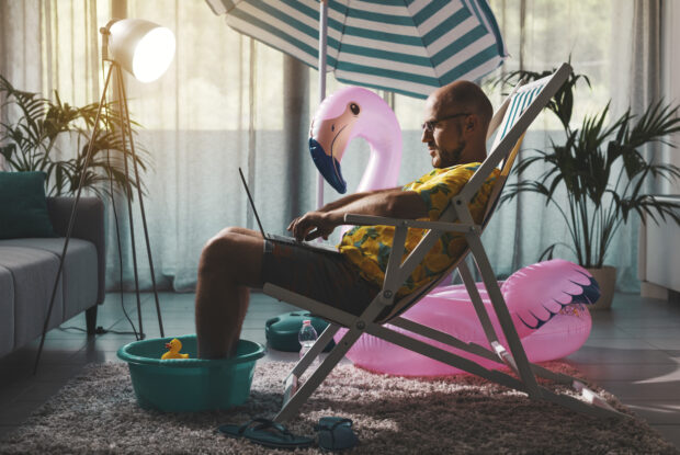 Mann arbeitet im Homeoffice im Sommer auf einem Liegestuhl