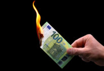 Männerhand hält brennenden Geldschein