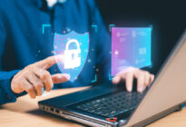 Hände an Laptop mit IT- Sicherheitszeichen