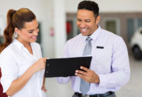 Junger Verkäufer zeigt junger Kundin Screen