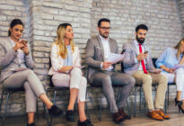 Frauen und Männer auf Stühlen bei der Jobsuche