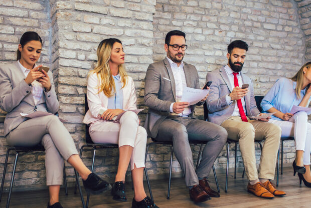 Frauen und Männer auf Stühlen bei der Jobsuche