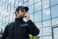 Security-Verantwortlicher steht mit Walkie-Talkie vor einem Gebäude