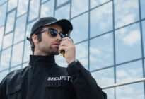 Security-Verantwortlicher steht mit Walkie-Talkie vor einem Gebäude