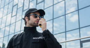 Security-Verantwortlicher steht mit Walkie-Talkie vor einem Gebäude