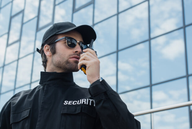 Security-Verantwortlicher steht mit Walkie-Talkie vor einem Gebäude